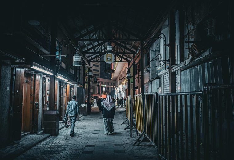 吾爱社区 像素方块风格的夜晚山谷营地，几处火把光照亮洞穴入口与木质小屋